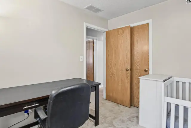 This room features a desk, chair, closet, and a crib.