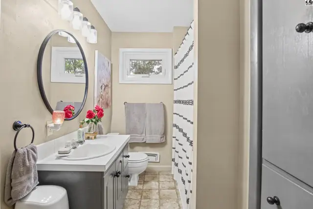 This bathroom features a vanity, toilet, and shower with a patterned curtain.