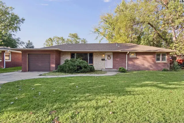Brick and stone ranch home with attached garage and mature landscaping.