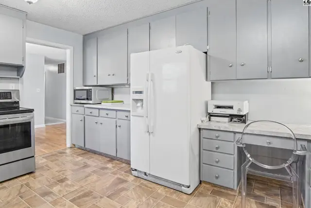 Kitchen features light gray cabinets, white appliances, and a built-in desk area.