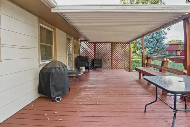 Covered wooden deck with built-in bench and lattice privacy screen.