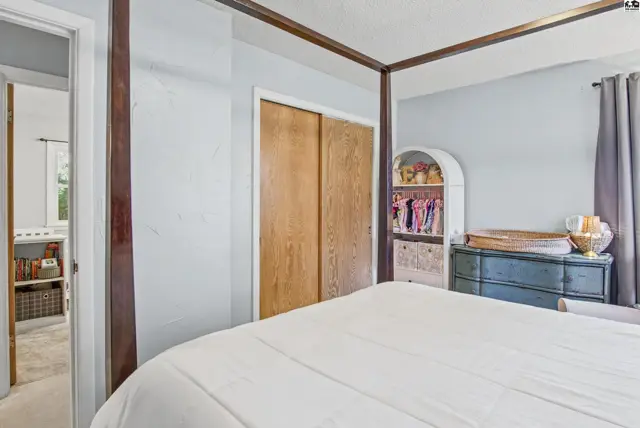 This bedroom features a four-poster bed, wooden closet doors, and a blue dresser.
