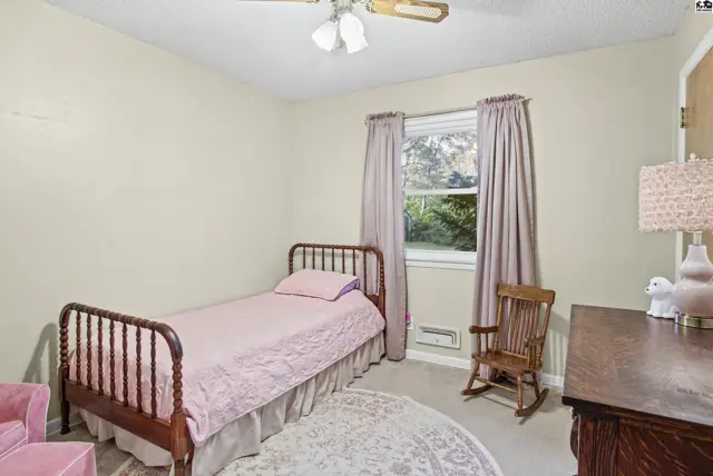 This bedroom features a metal bed frame, a rocking chair, and a dresser.
