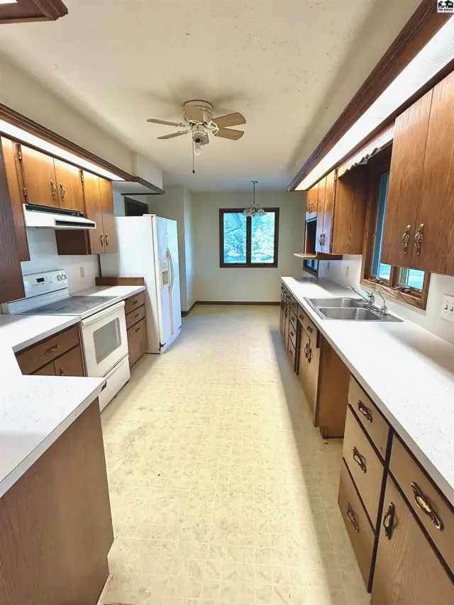 Spacious kitchen features wood cabinetry, white appliances, and ample counter space.
