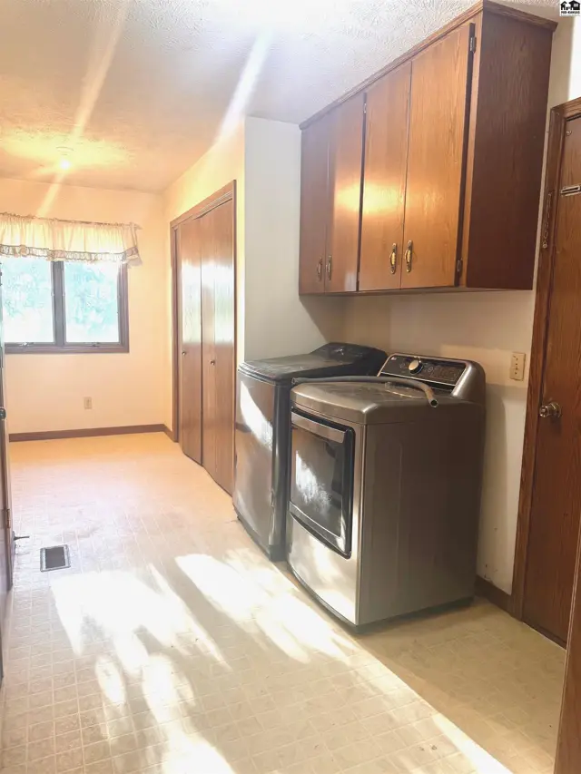 This room features a washing machine, dryer, and ample wood cabinetry.