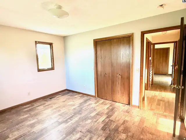 This room features wood-look flooring, a closet with double doors, and a small window.