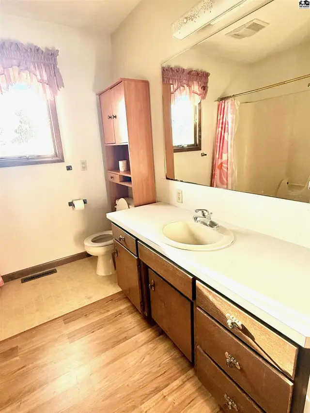 This bathroom features a vanity with a sink, a toilet, and a mirrored medicine cabinet.