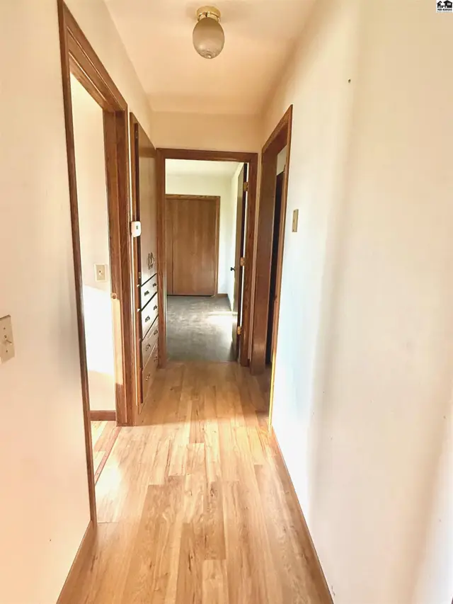 Hallway with wood-look flooring, white walls, and wooden doors.