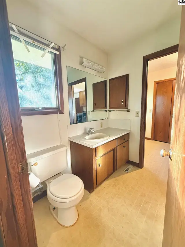 This bathroom features a toilet, vanity with sink, and wood-paneled cabinets.
