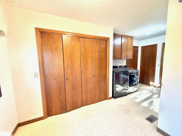 This room features a large closet, laundry machines, and overhead cabinetry.