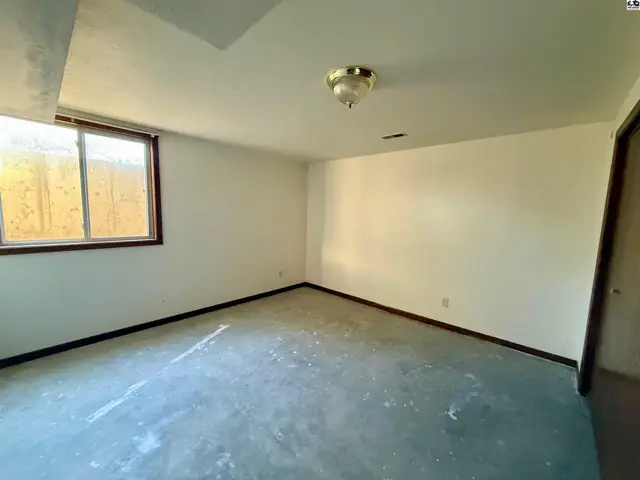 This room features a large window, carpeted floor, and a ceiling light fixture.