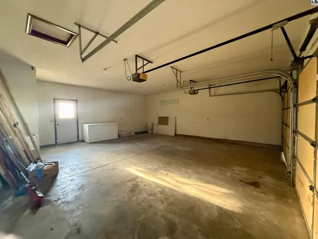 Spacious garage with concrete floor, two garage doors, and a side door.