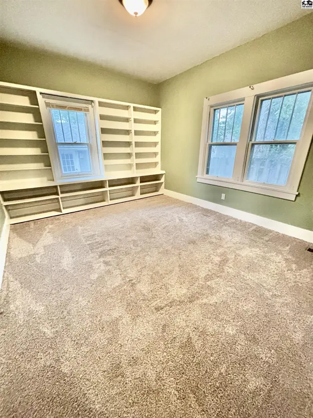 This room features carpeted floors, light green walls, and extensive built-in shelving.