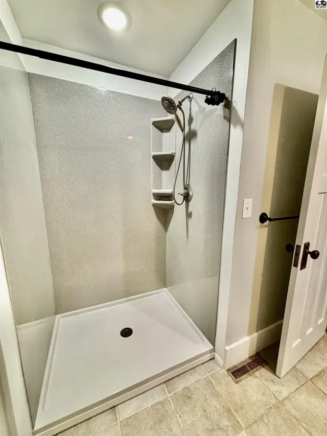 This bathroom features a spacious walk-in shower with a white base and tiled walls.