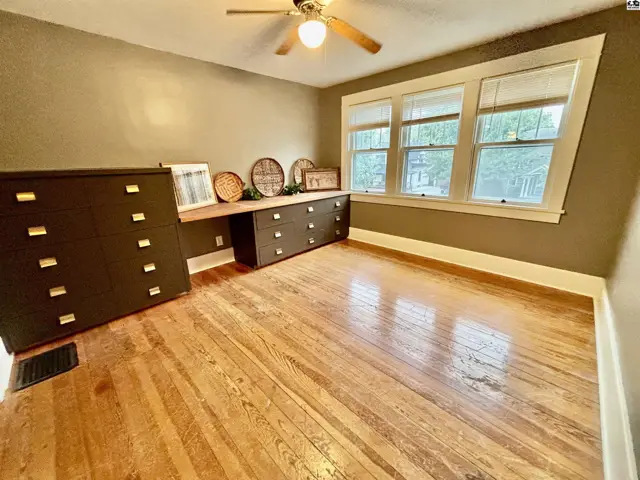This room features hardwood floors, a built-in desk, and large windows.