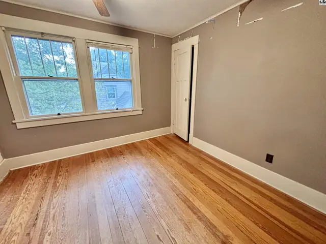 This room features hardwood floors, two windows, and a ceiling fan.