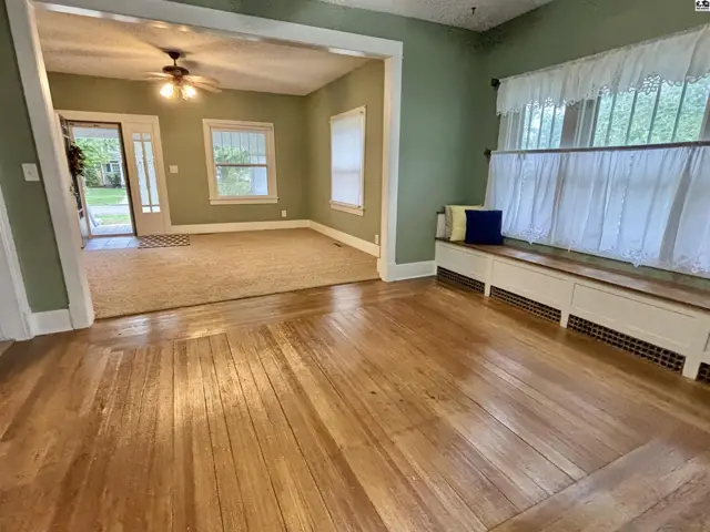 Hardwood floors and a built-in window seat complement the living room with a ceiling fan.