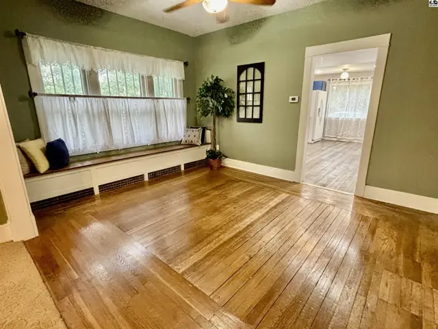 This room features hardwood floors, a built-in window seat, and a ceiling fan.