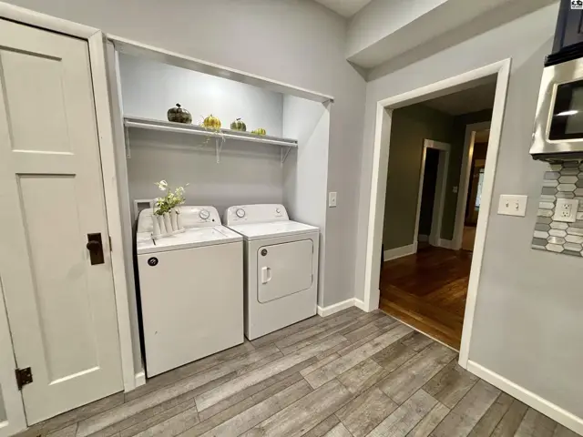 White washer and dryer set in a laundry alcove with wood-look flooring.