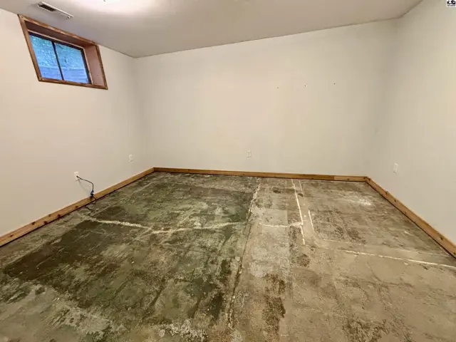 Unfinished basement room with concrete floor and a small window.