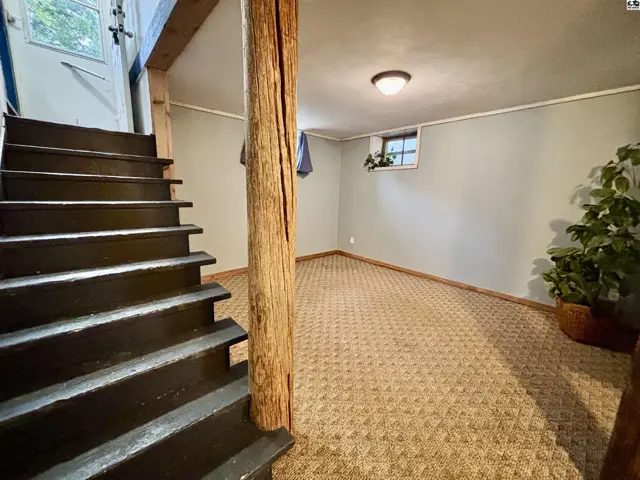 Carpeted room with a wood support beam and a small window.