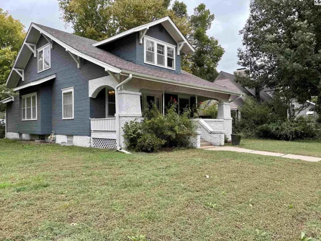 Blue clapboard house with a wraparound porch and gabled dormers.