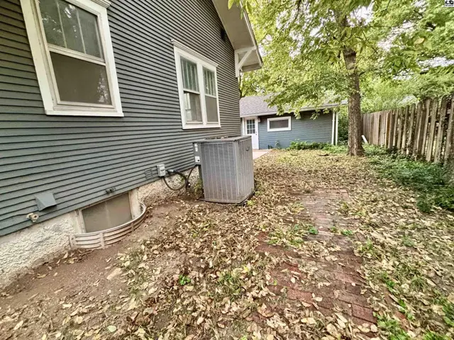 Exterior view shows a detached garage, brick patio, and mature trees.