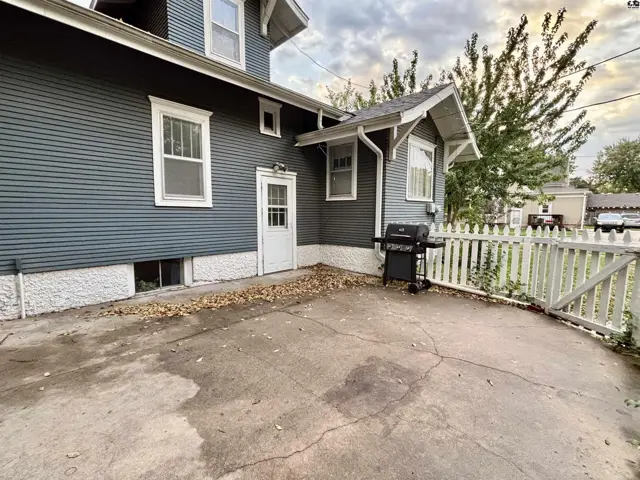 A concrete patio with a white picket fence surrounds the exterior of this blue-sided home.