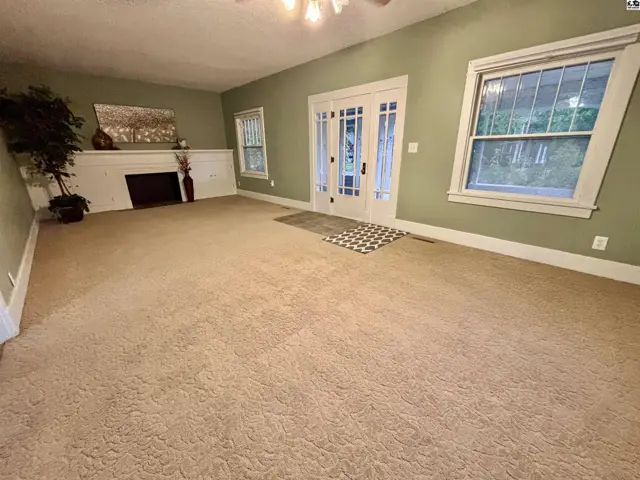 Spacious living room with a fireplace, large windows, and double glass doors.