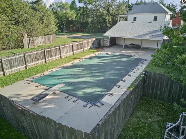 This property features a large, fenced backyard with a covered patio and a swimming pool.