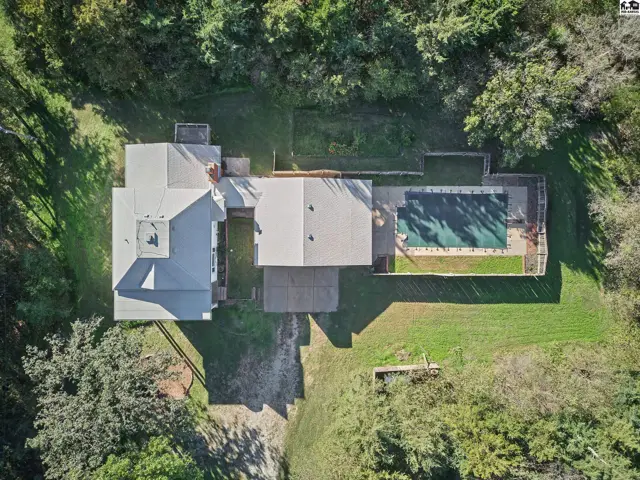 Spacious home with a swimming pool and expansive lawn surrounded by mature trees.