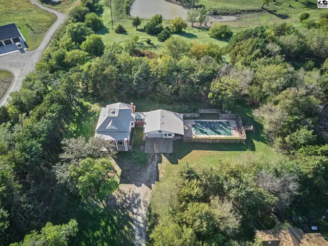 Spacious home with a pool and detached garage surrounded by mature trees.