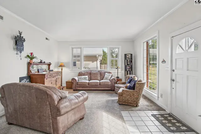 Spacious living room with carpet, large windows, and a white door.