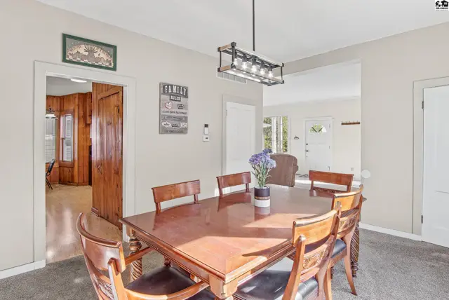 Spacious dining room with a wooden table, chairs, and a modern light fixture.