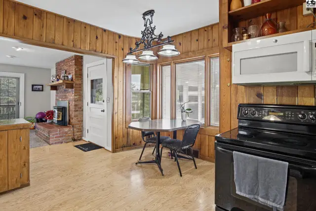 This kitchen features wood-paneled walls, a breakfast nook with a bay window, and a black range.