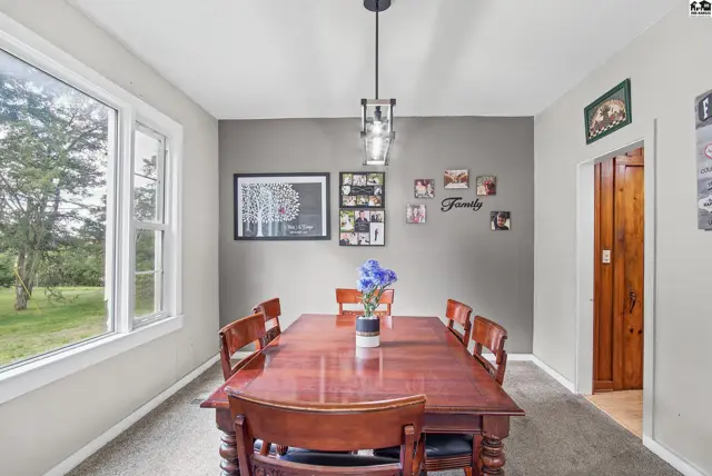 This dining room features a large window, wood table, and a modern pendant light.