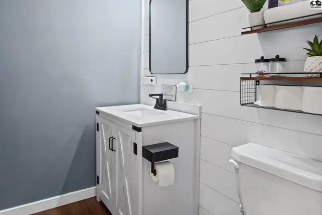 White vanity with black hardware and a white toilet are in this bathroom.