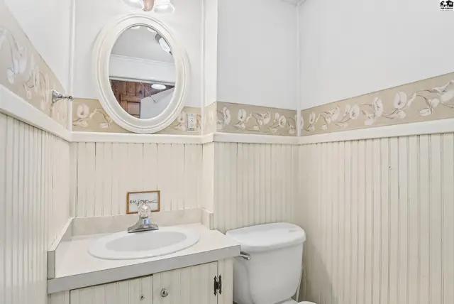 This bathroom features a vanity with a sink, a toilet, and an oval mirror.