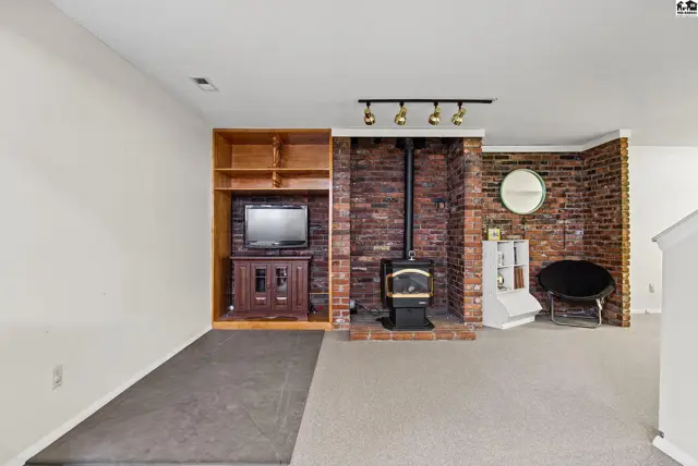This living area features a brick fireplace with a wood-burning stove and built-in shelving.
