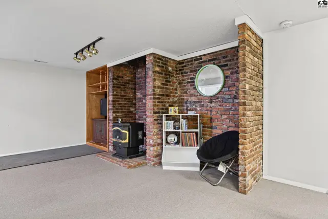 Brick accent wall surrounds a wood-burning stove and built-in shelving.