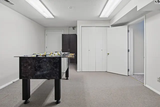 This finished basement features carpeted floors, white doors, and a foosball table.