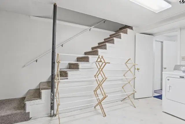 Carpeted stairs lead to a finished basement with a laundry area.