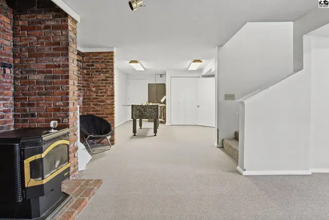 Spacious finished basement with brick fireplace, foosball table, and carpeted floors.