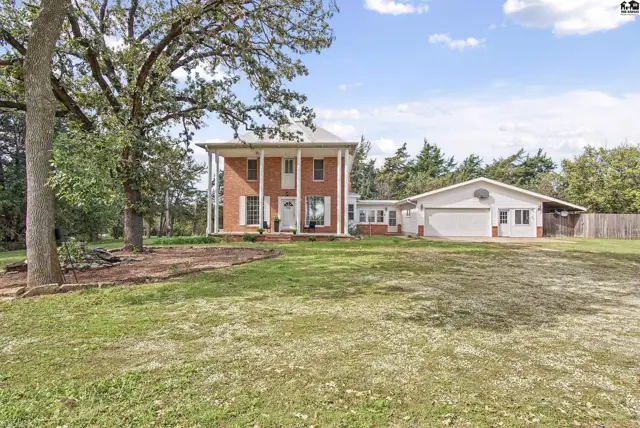 Brick home with a covered porch and attached garage sits on a grassy lot.
