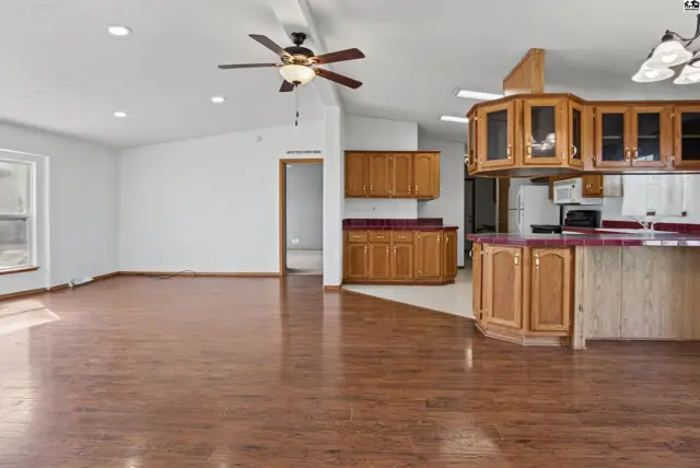 Spacious living area with wood flooring and an open-concept kitchen featuring oak cabinetry.