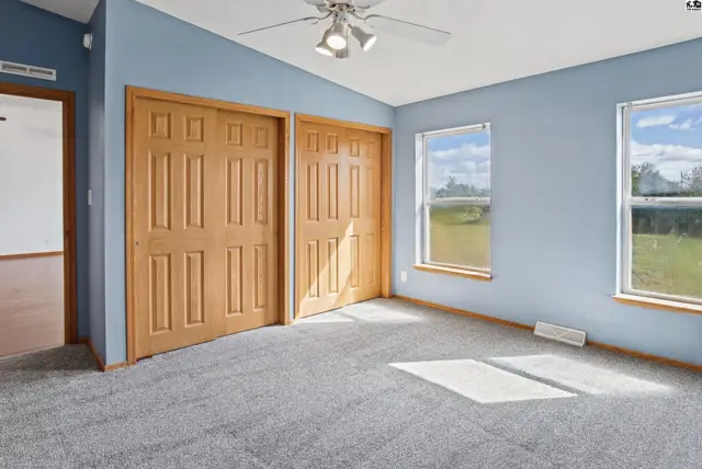 This room features light blue walls, a gray carpet, and two wooden closet doors.