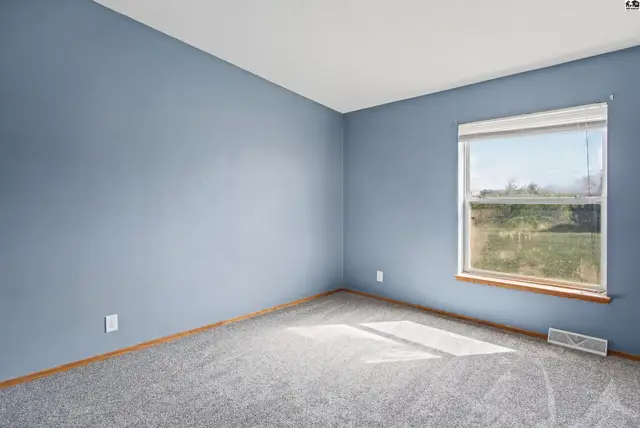 This room features light blue walls, grey carpet, and a large window.