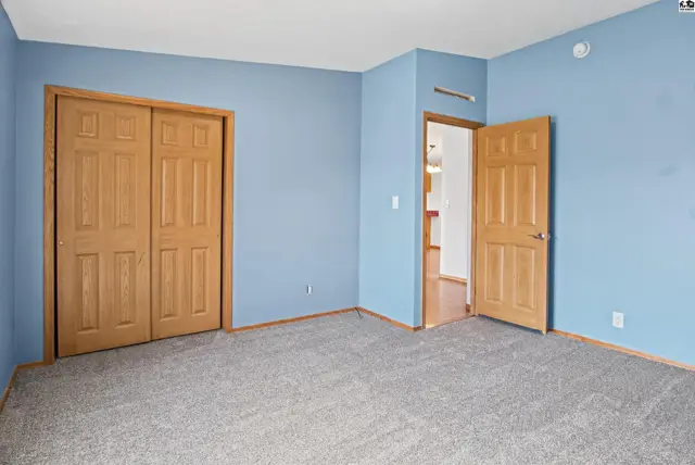 This room features light blue walls, a large closet with double wooden doors, and a doorway to another room.