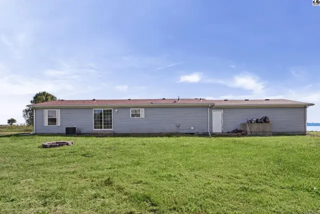 This single-story home features light blue siding, a brown roof, and a grassy yard.