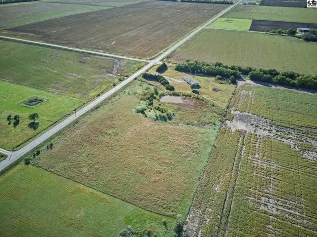Expansive rural property features a home, pond, and surrounding agricultural fields.